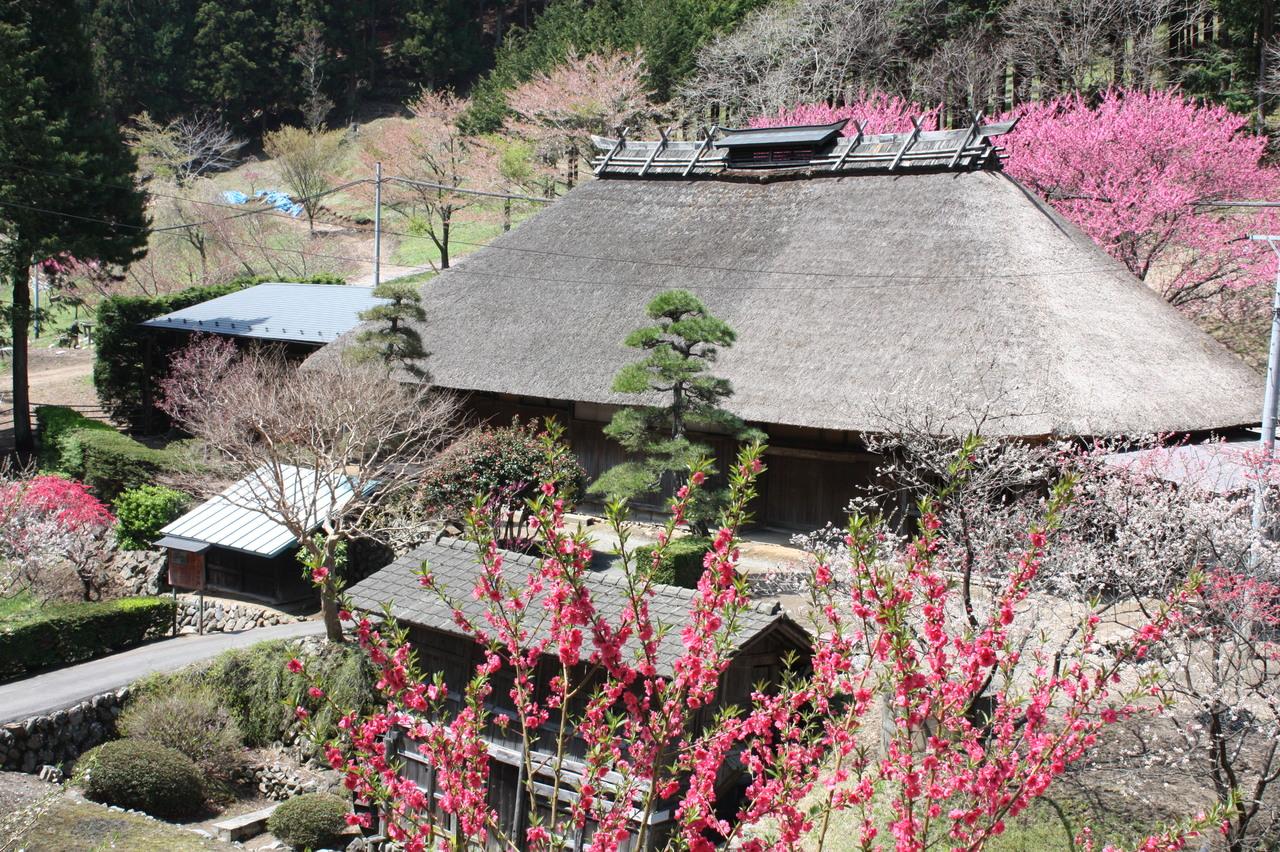 赤やピンクの花が周囲に咲く旧木下家住宅の外観写真
