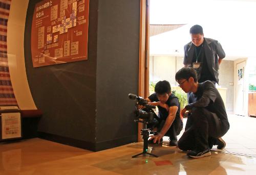 カメラの使い方を教わりながら撮影する生徒たち