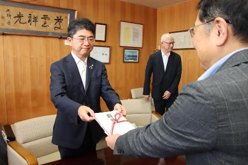 目録を手渡すケイティケイ株式会社の青山社長