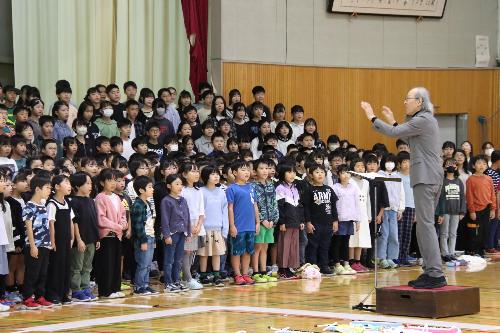 50周年記念ソングを歌う児童と指揮する唐澤さん