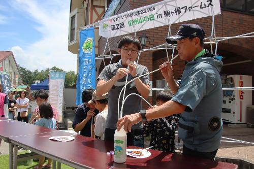 青空の下、牛乳を飲むタイムを競う参加者