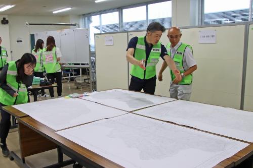 被害状況の報告をホワイトボードや図面にまとめる職員