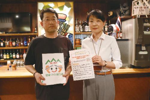 登録店の登録書を受け取った小田切さん（左）