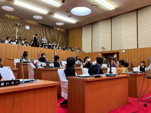 議員からの質問に回答しようと手を挙げる子どもたち