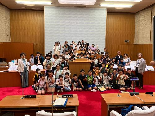 議会で議長席周辺に集まり写真を撮る子どもたち